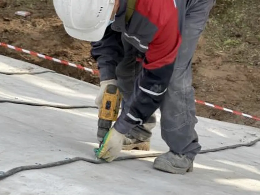 A worker running a screw gun along the overlap between two sheets